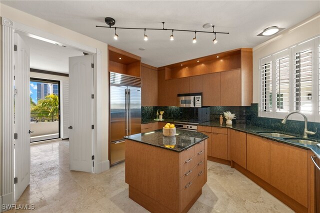 kitchen featuring a center island, appliances with stainless steel finishes, sink, dark stone countertops, and a healthy amount of sunlight