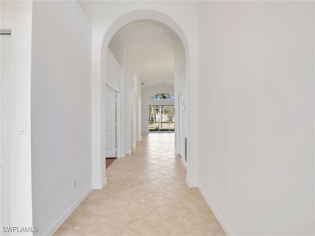 hallway featuring light tile patterned floors and lofted ceiling