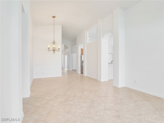 tiled spare room with a notable chandelier