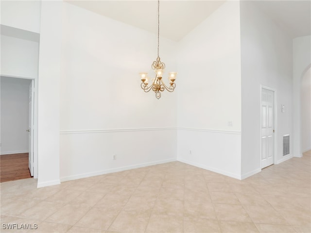 spare room with light tile patterned floors, high vaulted ceiling, and a notable chandelier