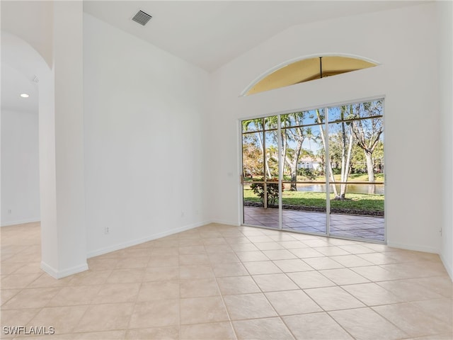 spare room with a water view, light tile patterned floors, and vaulted ceiling