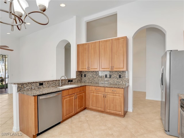 kitchen featuring sink, light stone countertops, appliances with stainless steel finishes, light tile patterned flooring, and kitchen peninsula