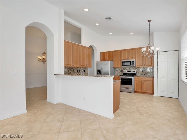 kitchen featuring appliances with stainless steel finishes, tasteful backsplash, light stone counters, pendant lighting, and an inviting chandelier