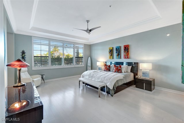 bedroom with a tray ceiling, ceiling fan, light wood-type flooring, and ornamental molding