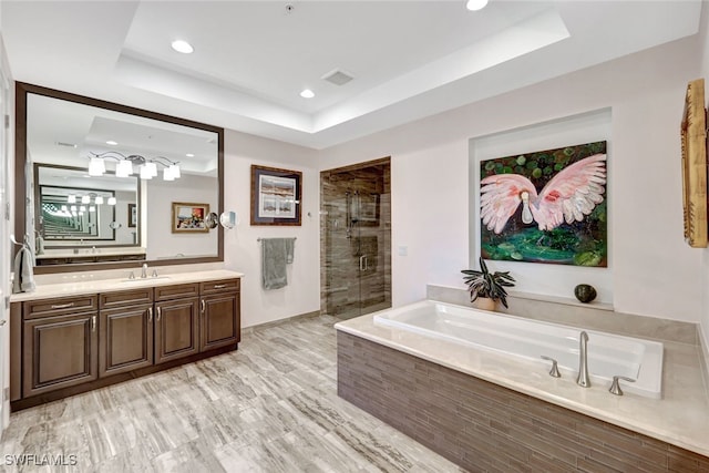 bathroom featuring hardwood / wood-style floors, vanity, separate shower and tub, and a raised ceiling