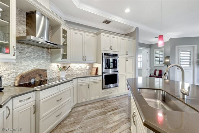 kitchen with tasteful backsplash, white cabinetry, wall chimney exhaust hood, and sink