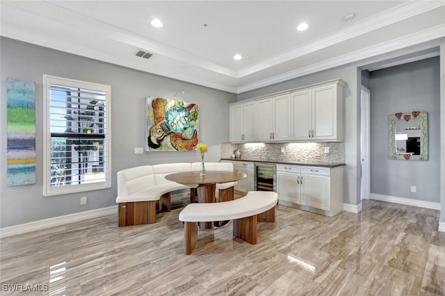 kitchen with white cabinetry, a tray ceiling, beverage cooler, and decorative backsplash