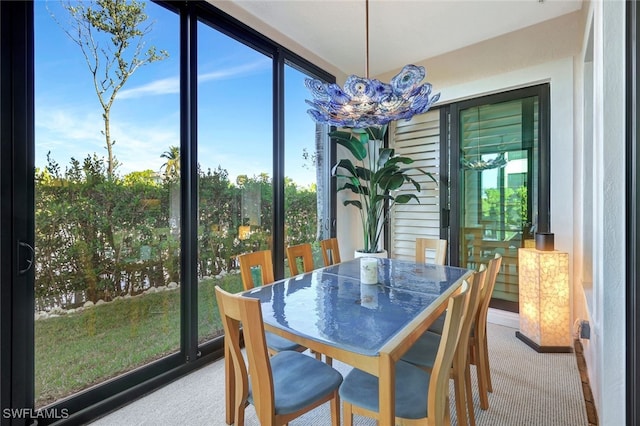 dining space featuring a wealth of natural light, light carpet, and a notable chandelier