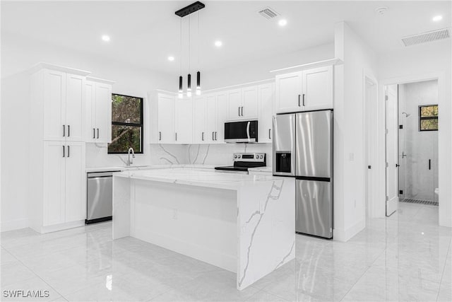 kitchen featuring a kitchen island, white cabinetry, hanging light fixtures, and appliances with stainless steel finishes