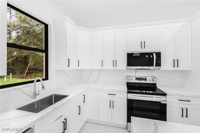 kitchen with sink, light stone counters, white cabinets, and stainless steel appliances