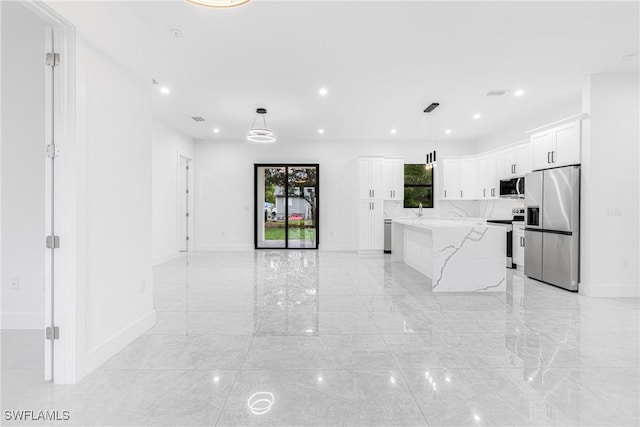 kitchen with white cabinetry, a center island, hanging light fixtures, and stainless steel appliances