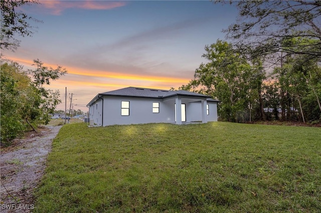 back house at dusk featuring a yard