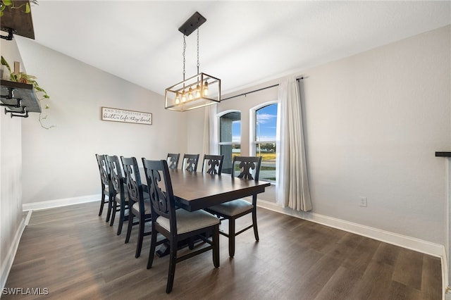 dining space featuring dark hardwood / wood-style flooring, lofted ceiling, and an inviting chandelier