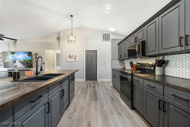 kitchen featuring wooden counters, appliances with stainless steel finishes, lofted ceiling, and gray cabinetry