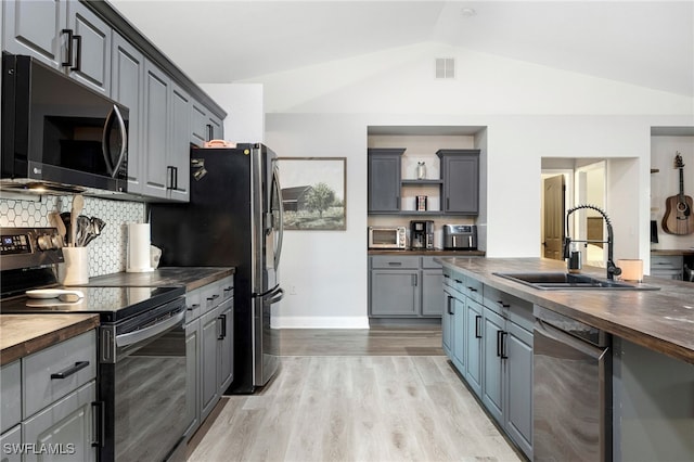 kitchen featuring butcher block counters, sink, stainless steel appliances, and lofted ceiling