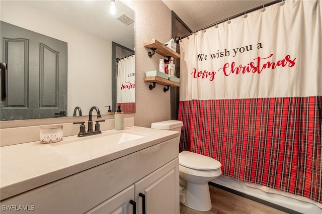 bathroom with hardwood / wood-style floors, vanity, a shower with curtain, toilet, and a textured ceiling