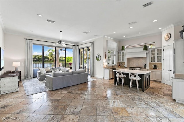 living room featuring ceiling fan, a water view, and ornamental molding