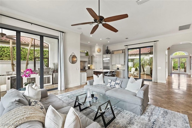 living area with plenty of natural light, crown molding, arched walkways, and baseboards