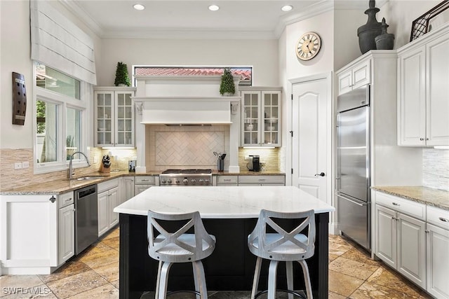 kitchen with stone tile flooring, crown molding, appliances with stainless steel finishes, and a sink