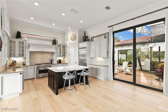 kitchen with a sink, visible vents, high quality appliances, a center island, and a kitchen bar