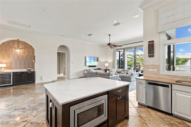 kitchen with tasteful backsplash, wine cooler, appliances with stainless steel finishes, and ornamental molding