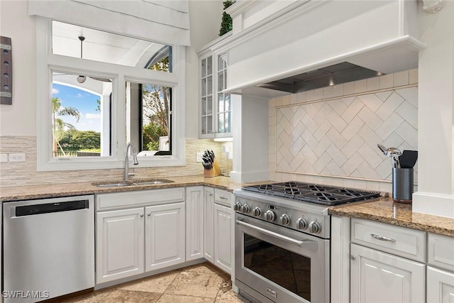 kitchen featuring appliances with stainless steel finishes, a sink, white cabinetry, and custom range hood