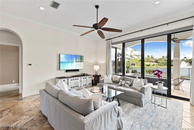 living room featuring plenty of natural light, visible vents, arched walkways, and crown molding