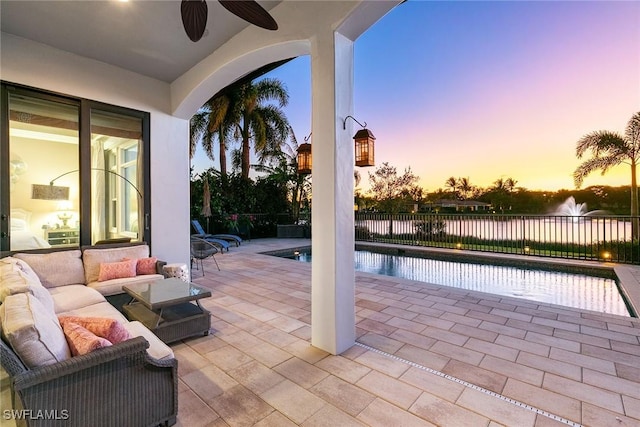 patio terrace at dusk featuring a fenced in pool, fence, an outdoor hangout area, and a ceiling fan