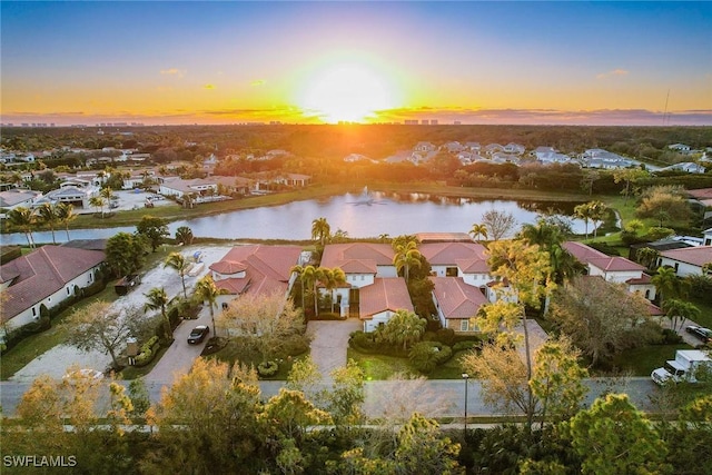 aerial view at dusk with a residential view and a water view