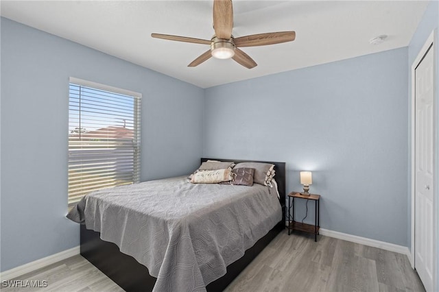 bedroom featuring ceiling fan, light hardwood / wood-style flooring, and a closet