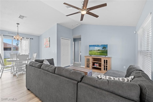 living room with ceiling fan with notable chandelier, light wood-type flooring, and vaulted ceiling