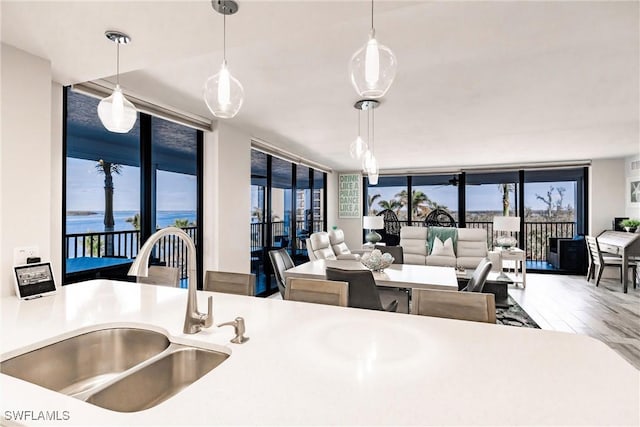 kitchen with decorative light fixtures, a water view, a wall of windows, and sink