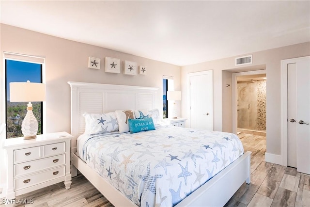 bedroom with connected bathroom and light hardwood / wood-style floors