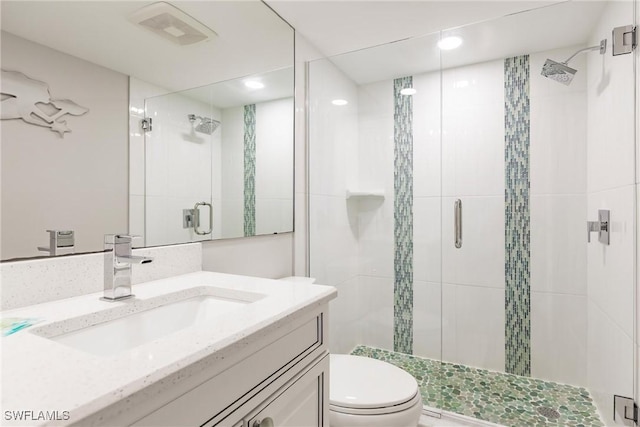 bathroom with a shower with door, vanity, and toilet