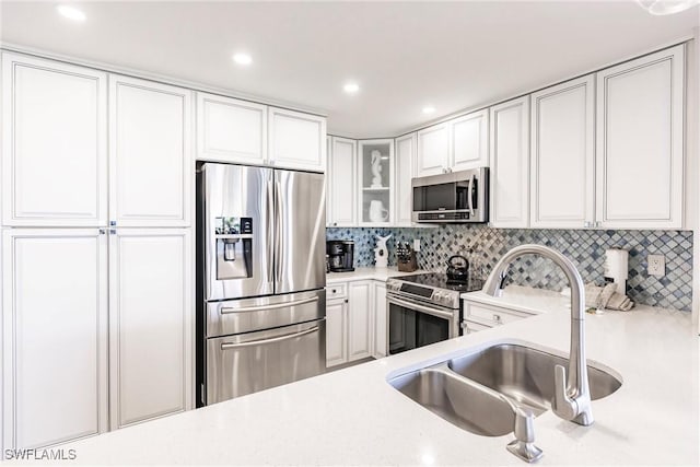 kitchen featuring white cabinets, stainless steel appliances, tasteful backsplash, and sink