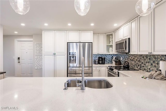 kitchen with decorative backsplash, white cabinets, stainless steel appliances, and decorative light fixtures