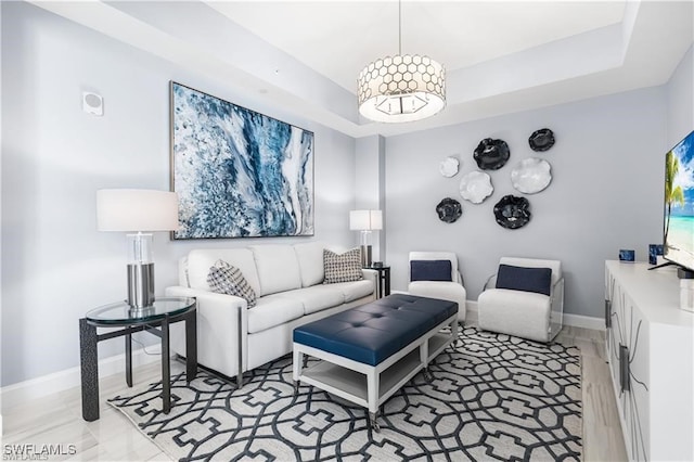 living room with a raised ceiling and light hardwood / wood-style flooring