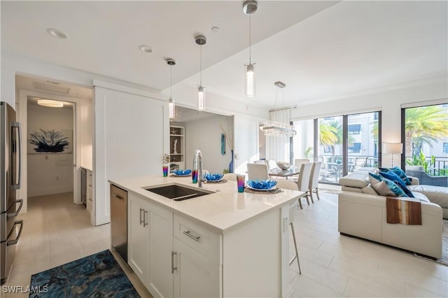 kitchen with a breakfast bar, white cabinets, sink, an island with sink, and decorative light fixtures