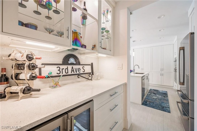 kitchen featuring white cabinets, sink, stainless steel appliances, and wine cooler