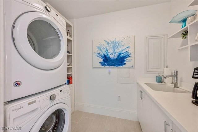 laundry room with cabinets, sink, light tile patterned floors, and stacked washing maching and dryer