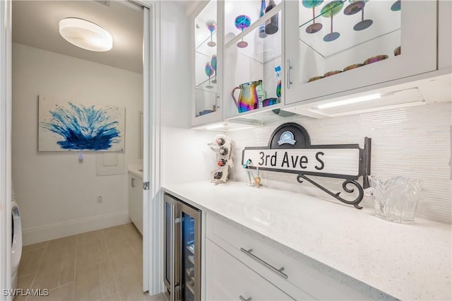 bar with white cabinetry, beverage cooler, and light stone counters