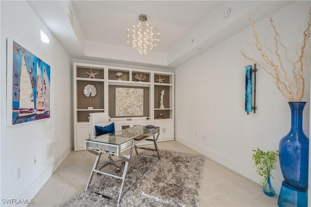 office area featuring a raised ceiling, built in shelves, light tile patterned floors, and an inviting chandelier