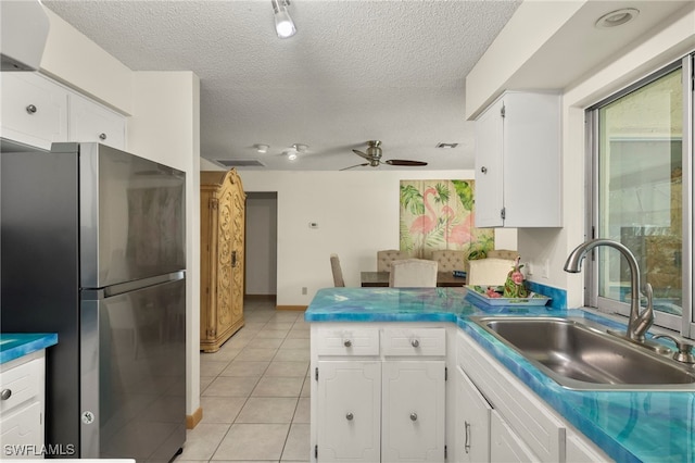 kitchen with ceiling fan, white cabinetry, sink, and stainless steel refrigerator