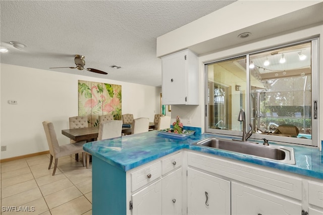 kitchen with ceiling fan, sink, light tile patterned floors, a textured ceiling, and white cabinets