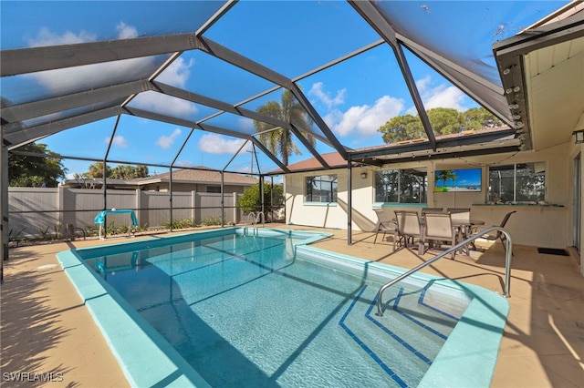 view of pool with glass enclosure and a patio area