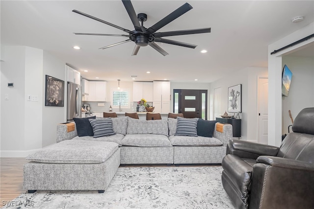 living room with ceiling fan, sink, and light hardwood / wood-style floors