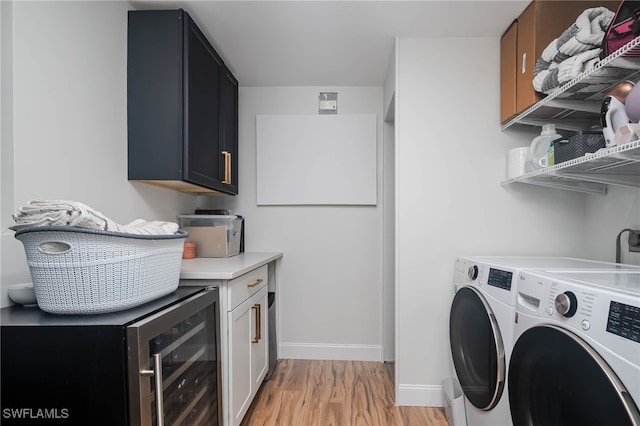 laundry room featuring washer and dryer, light wood-type flooring, wine cooler, and cabinets