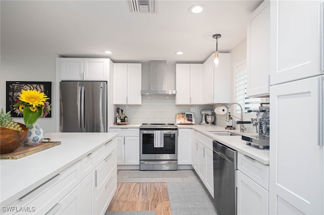 kitchen with white cabinets, wall chimney exhaust hood, sink, and appliances with stainless steel finishes