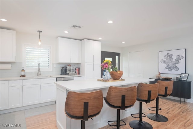 kitchen featuring decorative backsplash, sink, white cabinets, and decorative light fixtures