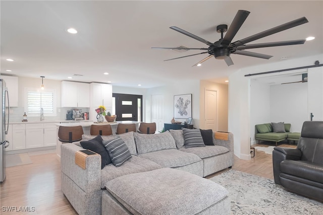 living room with ceiling fan, sink, and light hardwood / wood-style flooring